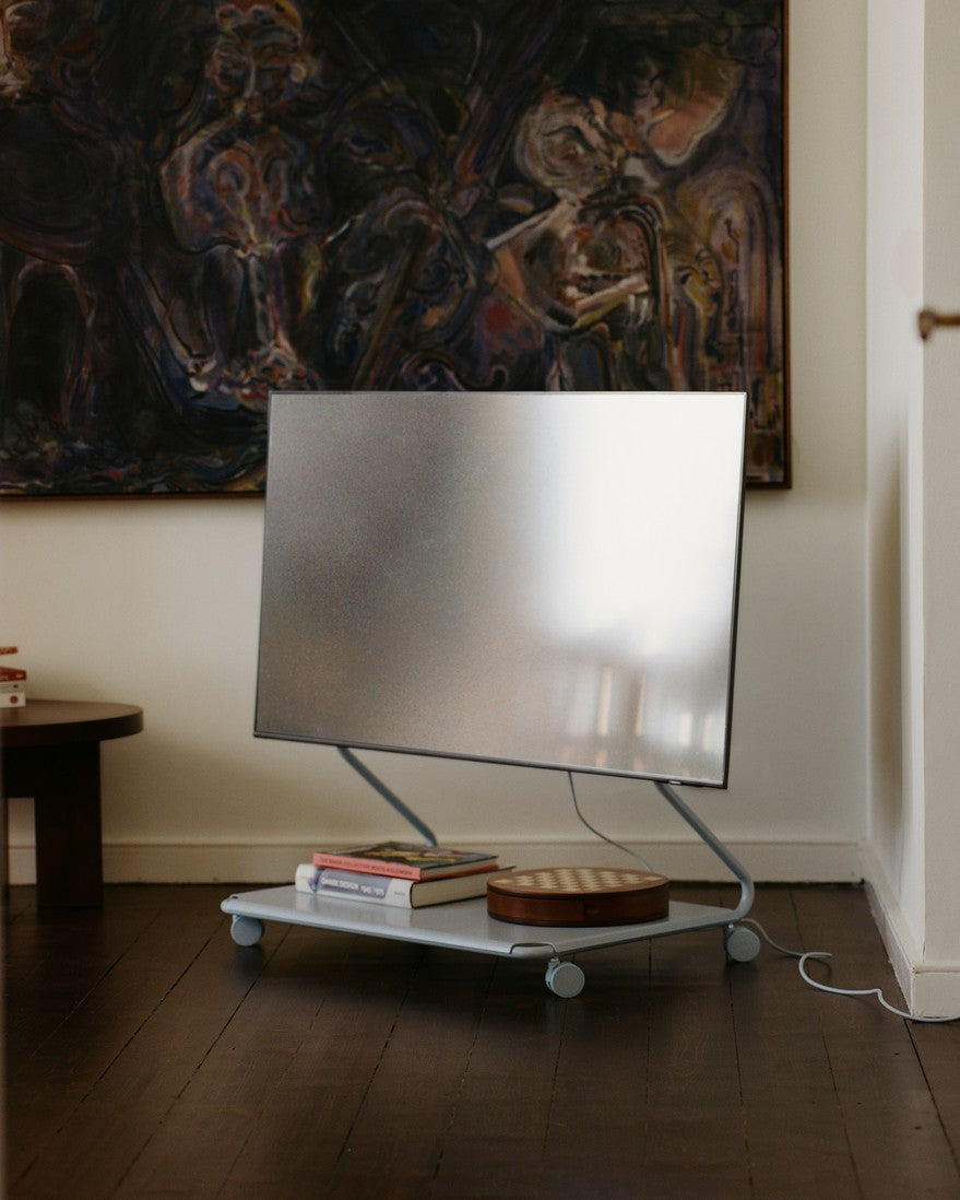 Disco in Powder Blue mit Fernseher im Wohnraum, Rollen auf Holzboden, Bücher und Schale auf der Ablage